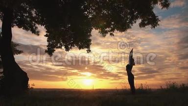 一位女子在美丽的日出练习瑜伽的剪影